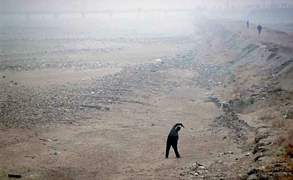 Baotou, Inner mongolia CHina Yellow river tributary is dry. old man does morning exercises on dry river bed Picture Credit : Dermot Tatlow