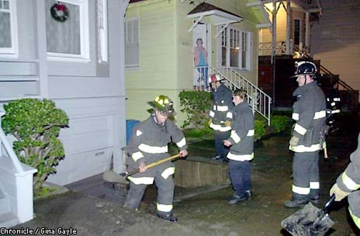 Jean Ostrander watches as firefighters carry the dirt that washed down the street from a basement level garage on California after a watermain broke at California near 28th street. Photo by Gina Gayle/The SF Chronicle.