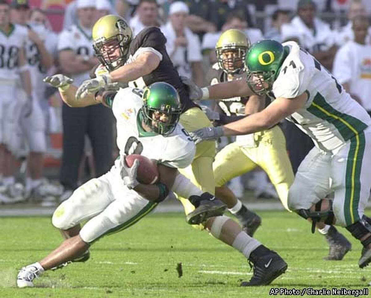 Oregon tailback Maurice Morris (9) runs with the ball as offensive tackle Jim Adams (71) blocks Colorado's Terrence Wood, left, and Tyler Brayton, second from right in the second quarter Tuesday, Jan. 1, 2002 at the at Sun Devil Stadium in Tempe, Ariz. ( AP Photo / Charlie Neibergall)