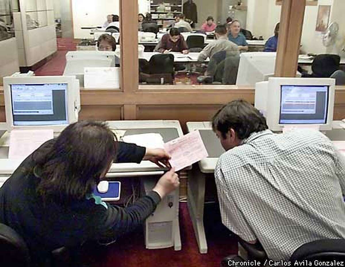 Temporary election workers, Sachi Manalisay, left, and Dmeetri Chames, right, look over a provisional ballot at the Department of Elections at San Francisco City Hall on Thursday, December 16, 1999. a battalion of election workers are counting the remaining thousands of provisional ballots which could take about two weeks. BY CARLOS AVILA GONZALEZ/THE CHRONICLE