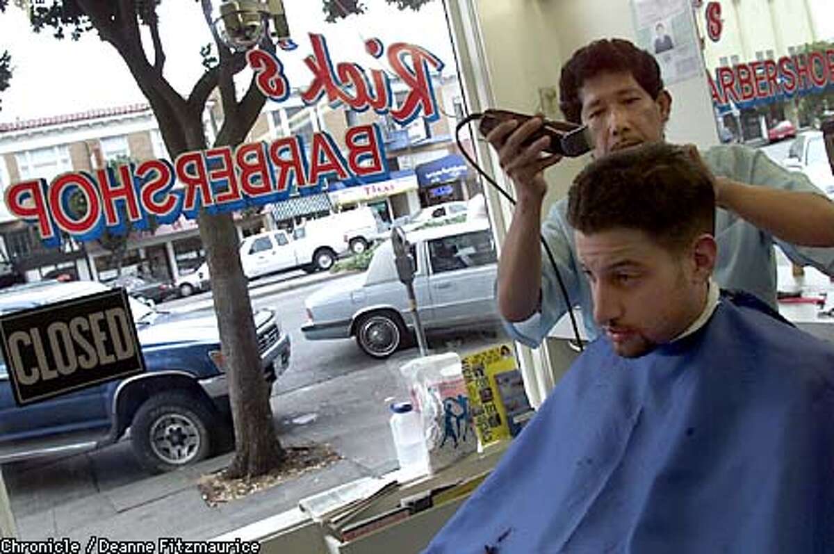 Ceasar Velasco, whose brother runs Rick's Barbershop on San Francisco's Geary Street, gives a haircut to Ryan Gonzalez, who has been coming to this shop for 10 years or so. CHRONICLE PHOTO BY DEANNE FITZMAURICE