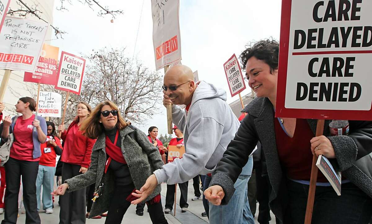Mental helth care workers L to R Victoria Bravo, Roscoe Simmons and Jessie Cohen dance to a song during a rally of registered nurses and nurse practitioners marched out front of Oakland's Kaiser Permanente Hospital. Tuesday, January 31, 2012.