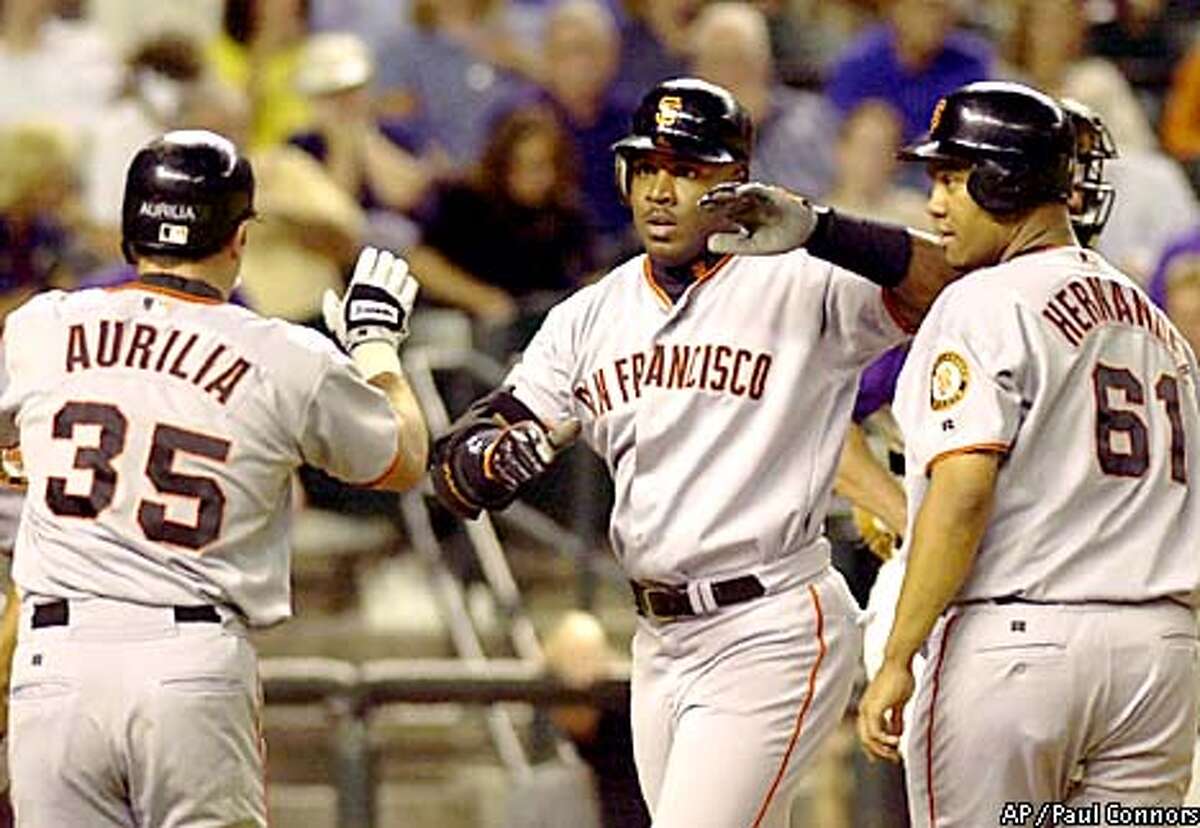San Francisco Giants slugger Barry Bonds, center, is congratulated by teammates Rich Aurilia, left, and Livan Hernandez, right, after hitting a grand slam off Arizona Diamondbacks pitcher Curt Schilling in the fifth inning Thursday, July 26, 2001, at Bank One Ballpark in Phoenix. The home run was Bonds' 44th of the season and second of the game.(AP Photo/Paul Connors)