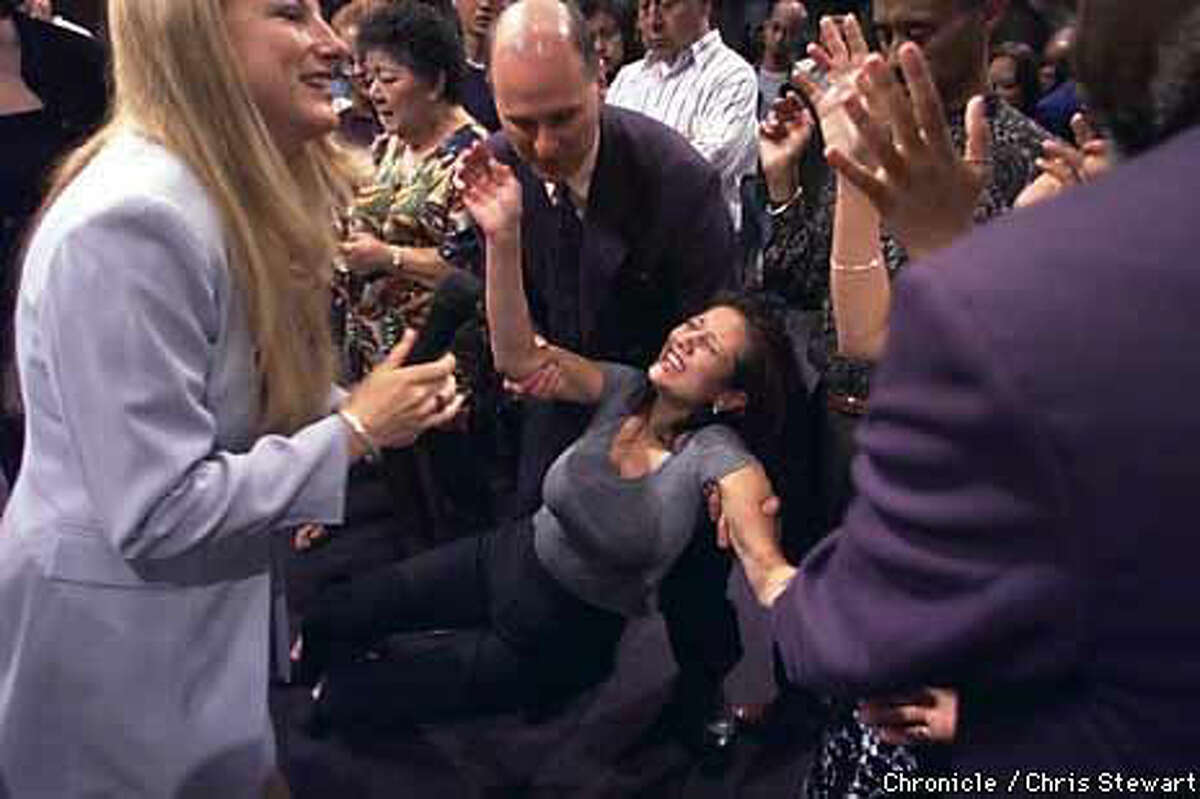 A woman was overcome during a laying on of hands by the Rev. Carla Bernal (left) during a service at Jubilee Christian Center in San Jose. Chronicle Photo by Chris Stewart