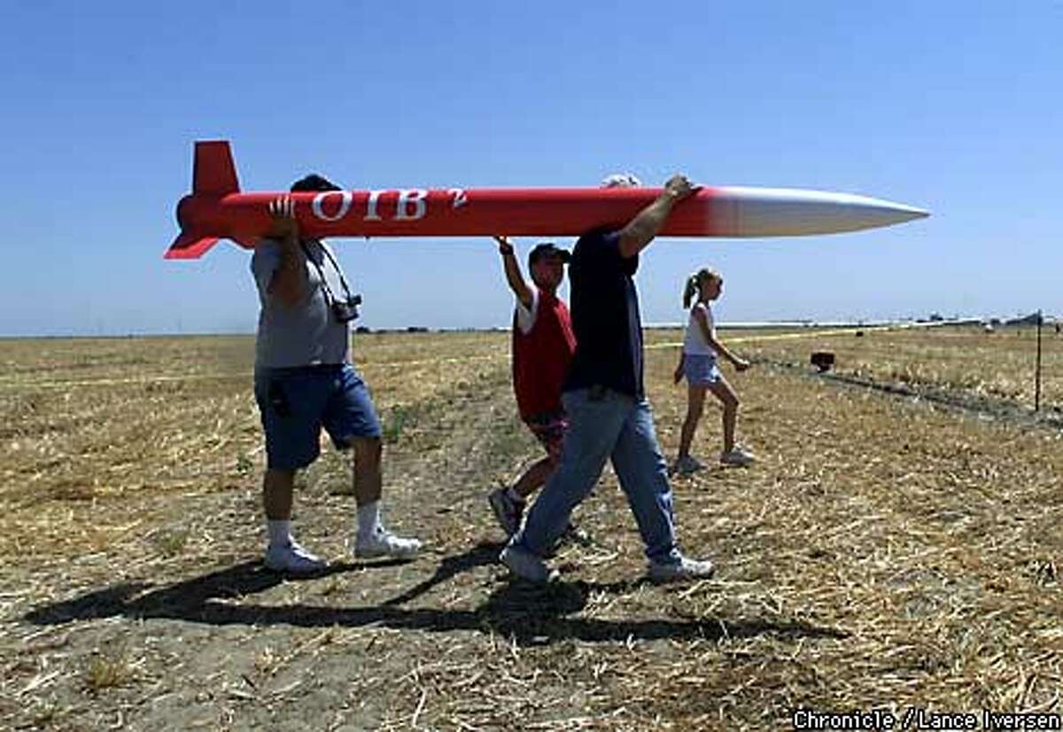 ROCKETSXX-11-C-19MAY01-MT-LI Big boys and their toys: friends and family of Richard Salinas owner of OIB ( O It's Big ) walk back to the staging area after a successful flight reaching 3,500 feet in Fresno Saturday. Model rocketry buffs from all over Northern Calif, gathered in Fresno 5/19/01 for the annual Dairy Aire High Powered model rocketry launch. By LANCE IVERSEN/SAN FRANCISCO CHRONICLE
