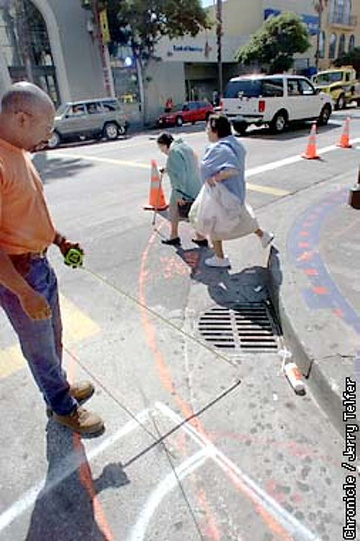 Steven Bowles (left), a field superintendent for subcontractor EG Construction, works out how the storm drain will be preserved at the 23rd & Mission Street pedestrian "bulge-out" being built as a pedestrian safety enhancement. DPT has announced a citywide program of street improvements to improve safety. CHRONICLE STAFF PHOTO BY JERRY TELFER