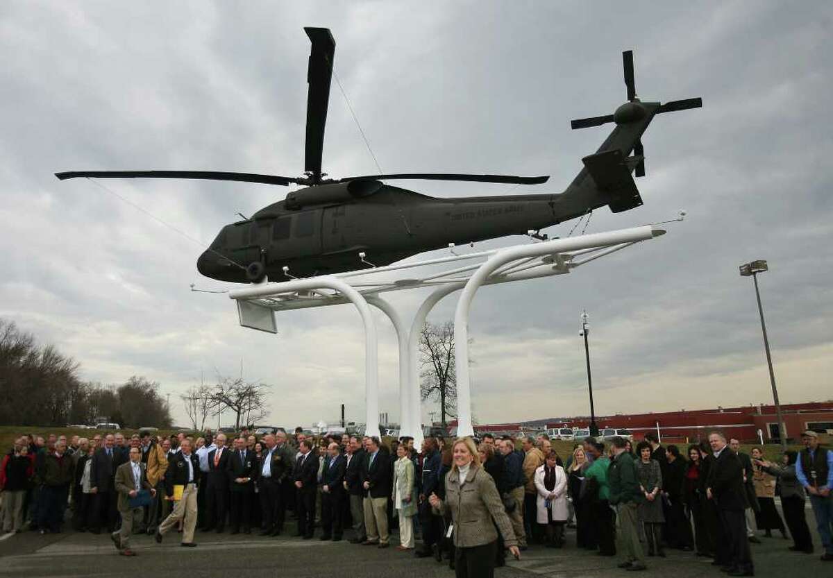 Sikorsky employees gather for a group photo beneath the UH-60 Black Hawk helicopter unveiled in front of the company headquarters and factory on Main Street in Stratford on Wednesday, February 1, 2012.