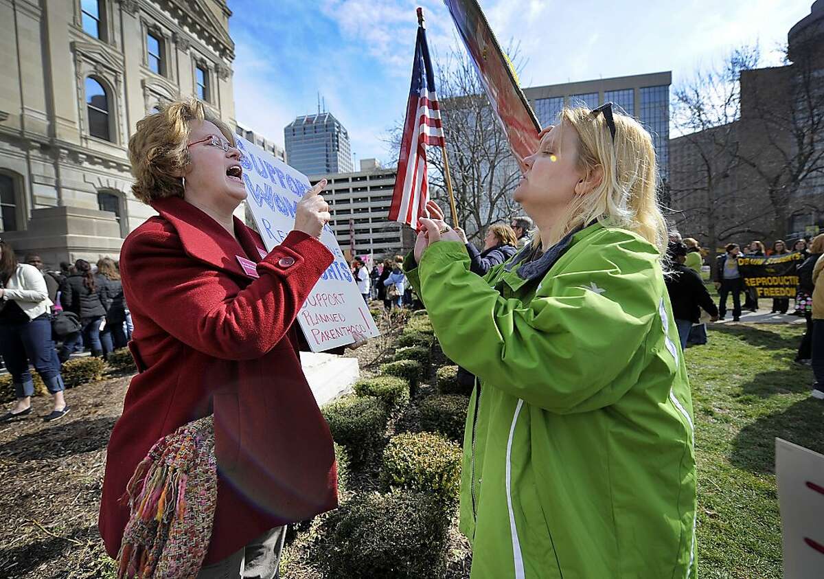 In this Tuesday, March 8, 2011 file photo, Planned Parenthood supporter Peg Paulson of Carmel, Ind., left, and opponent Heather Pruett of Indianapolis argue during a rally at the Indiana Statehouse on the South Lawn in Indianapolis in response to an Indiana House bill which would end funding to Planned Parenthood because it provides abortions. The nation's leading breast-cancer charity, Susan G. Komen for the Cure, is halting its partnerships with Planned Parenthood affiliates in 2012 - creating a bitter rift, linked to the abortion debate, between two iconic organizations that have assisted millions of women. Planned Parenthood says the cutoff, primarily affecting grants for breast exams, results from Komen bowing to pressure from anti-abortion activists. Komen says the key reason is that Planned Parenthood is under investigation in Congress - a probe launched by a conservative Republican who was urged to act by anti-abortion groups. (AP Photo/The Indianapolis Star, Alan Petersime)