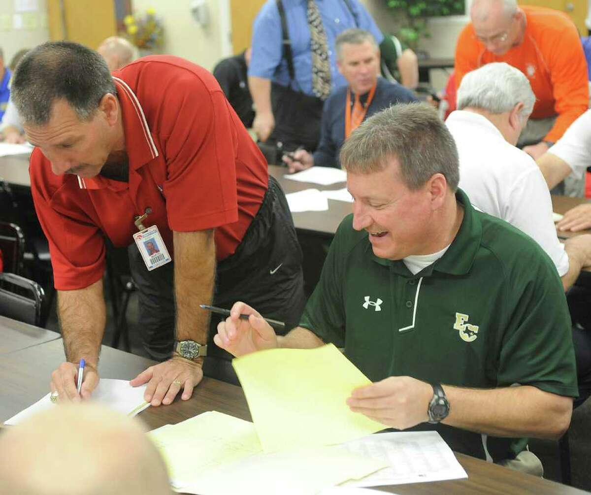Hardin Jefferson head coach David Martel, left, and East Chambers coach Russ Sutherland, right, look over their schedules and the realignment paperwork. The high school sports realignment from the UIL was released at 9:00 am Thursday morning. Coaches from the area gathered at the Region 5 education service center in Beaumont for the release of the districts and to plan scheduling of games for next season. Dave Ryan/The Enterprise