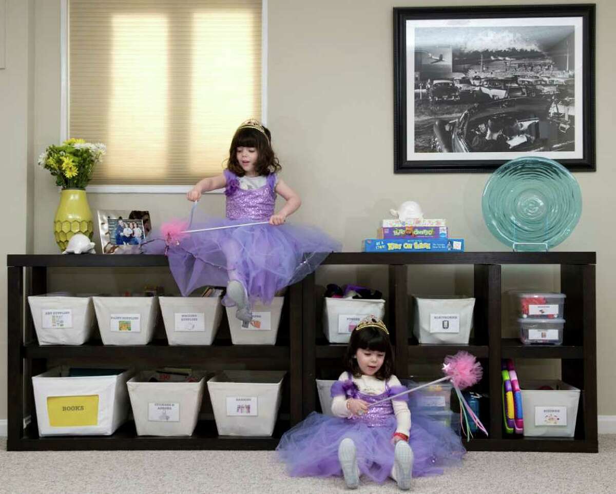 Professional organizer Rachel Strisik's 4-year-old twins, Marin, left, and Ellie play dress-up in their playroom. Labeled canvas bins make it easier for the girls to put toys back where they belong.
