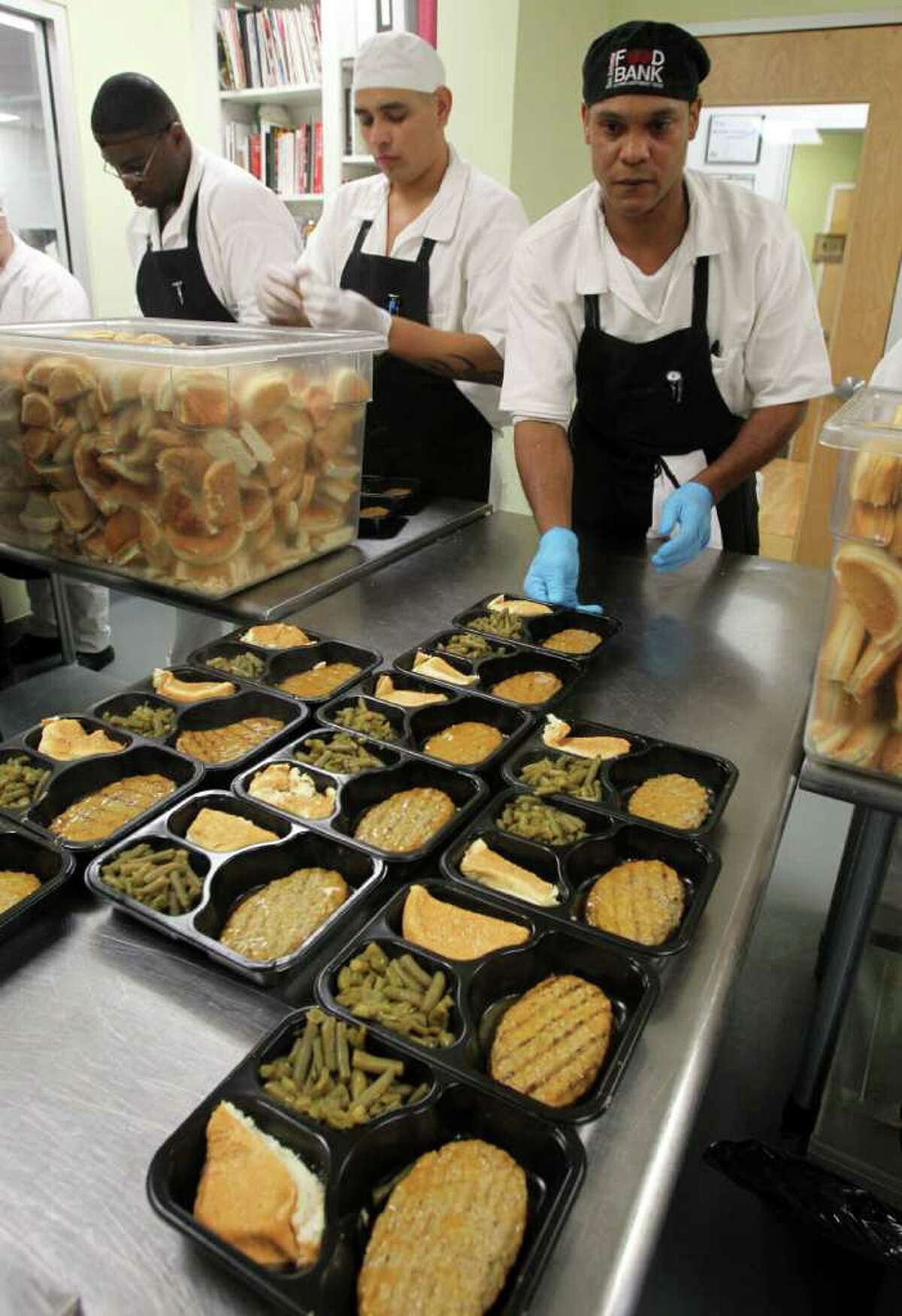 Prison inmate James Thomas (right) moves trays of food at the San Antonio Food Bank that will be fed to kids in after school programs. Inmates learn culinary skills in the Community Kitchen program and prepare 800 to 900 meals a day. The inmates are from the Torres Unit near Hondo, Texas. JOHN DAVENPORT/jdavenport@express-news.net