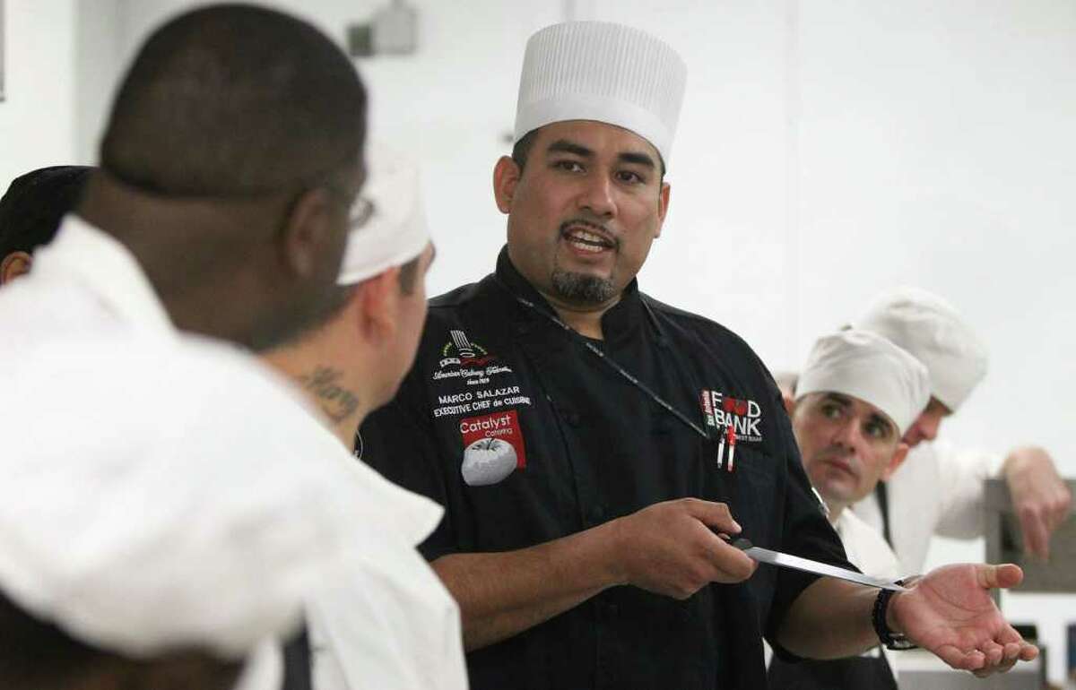 Marco Salazar, (wearing black and chef's hat) Executive Chef de Cuisine at the San Antonio Food Bank, teaches inmates from the Texas Department of Criminal Justice's Torres Unit about knives and cutlery used in a professional kitchen. About 11 to 12 inmates or trustees from the Torres unit are in a program at the San Antonio Food Bank called the Community Kitchen that teaches them a skill that will allow them to start anew when they are finished serving time. The inmates also take part in a program called Kids Kitchen where they prepare about 800 to 900 meals a day that are delivered to after school programs such as Communities in Schools and the Y.M.C.A. (Monday December 12, 2011) JOHN DAVENPORT/jdavenport@express-news.net