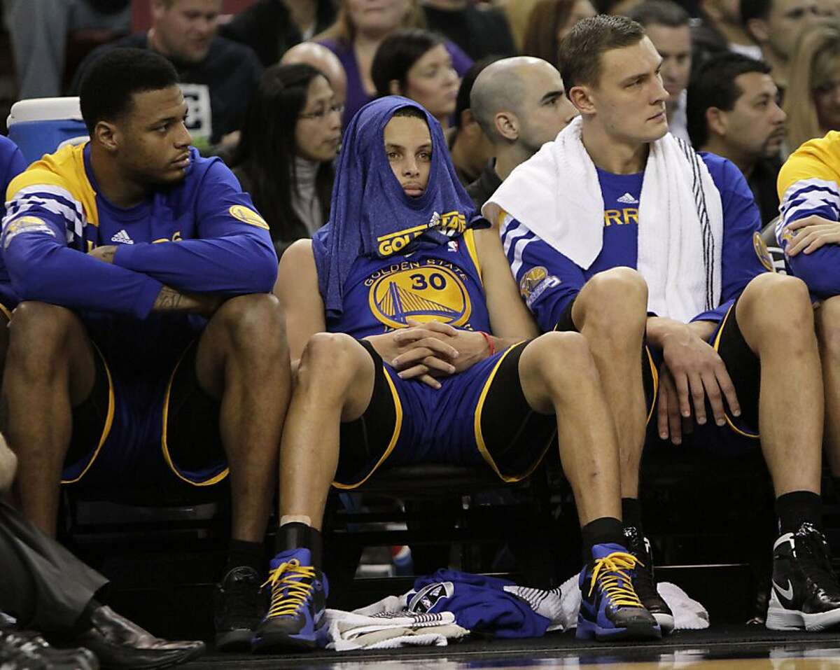 Golden State Warriors guard Stephen Curry, center, sits on the bench during the fourth quarter of an NBA basketball game against the Sacramento KIngs in Sacramento, Calif., Saturday, Feb. 4, 2012. The Kings won in overtime 114-106.(AP Photo/Rich Pedroncelli)