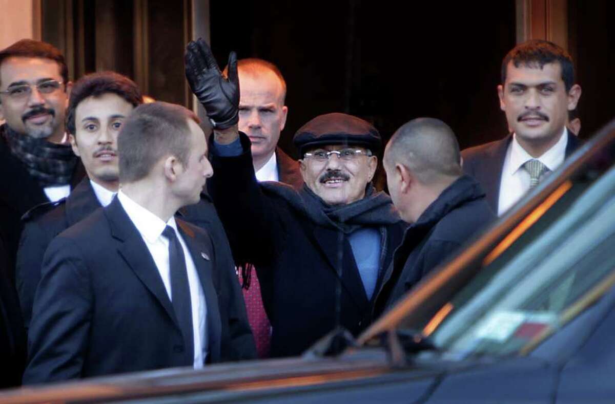 Yemeni President Ali Abdullah Saleh waves to people protesting his presence in the United States as he exits his hotel in New York, Sunday, Feb. 5, 2012. Saleh arrived in the United States on Saturday, Jan. 28, 2012, for treatment of burns he suffered during an assassination attempt in June. Human Rights Watch, a New York-based human rights organization says it has documented the deaths of hundreds of anti-government protesters in confrontations with Saleh's security forces, and while they are not opposed to Saleh receiving care in the United States, the organization wants assurances that concerned governments will insist on prosecution for those responsible for last year's attacks. (AP Photo/Seth Wenig)