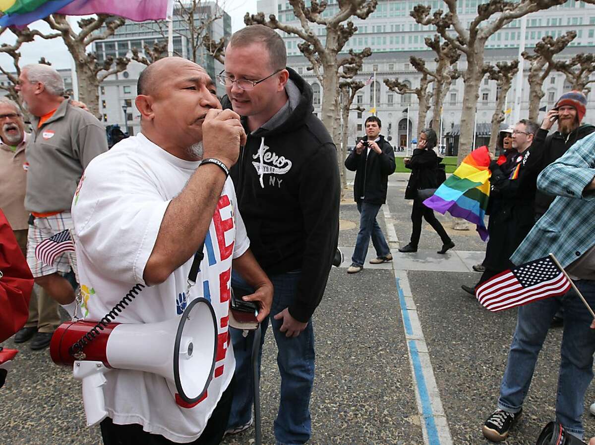Solonua Solonua, left, is confronted by a same-sex activist, while he preaches at couples as they walk towards City Hall, Tuesday February 7, 2012, to celebrate the 9th U.S. Circuit Court of Appeals ruling that Proposition 8 in unconstitutional, in San Francisco, Calif.