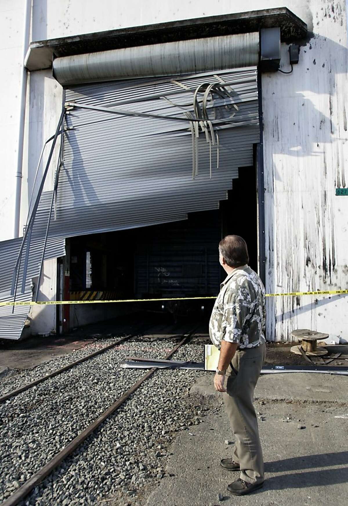 Insurance adjuster Richard Reimche inspects a rollup door which was apparently blown out from the intense heat. ATF agents continue to investigate a warehouse blaze on 10/14/05 in Vallejo, Calif. More than $100 million in wine, including stock of several well-known Bay Area wineries, was destroyed by a blaze that burned through a former torpedo bunker turned wine warehouse on Mare Island Wednesday.