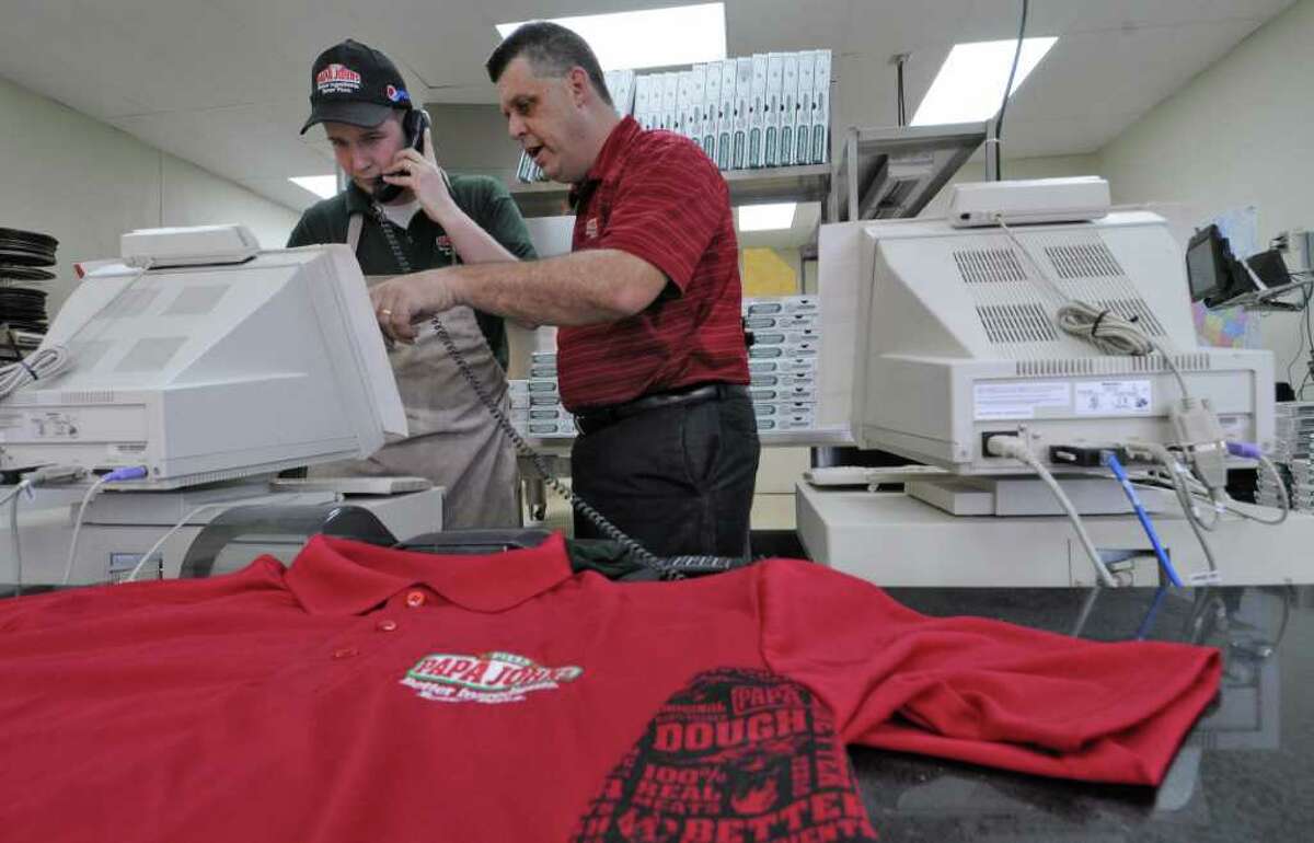Rick Young, operating partner for the Papa John's pizza on Troy Schenectady Road, right, works with shift leader Jeremy Dudley, near an employee workshirt, on Tuesday Feb. 7, 2012 in Latham, NY. The state fined the store $5000 for not having enough work shirts for their employees. (Philip Kamrass / Times Union )