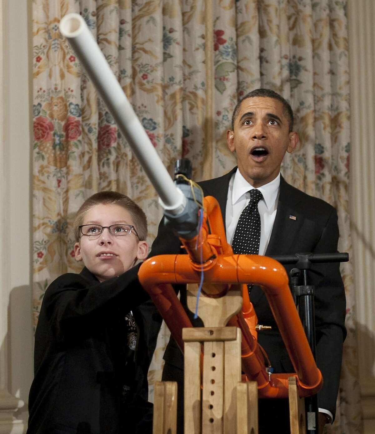 US President Barack Obama reacts as 14-year-old Joey Hudy of Phoenix, Arizona, launches a marshmallow from Hudy's "Extreme Marshmallow Cannon" during a tour of the White House Science Fair in the State Dining Room of the White House in Washington, DC, February 7, 2012. Obama announced new policies to recruit and support science, technology, engineering and math (STEM) teacher programs, including requesting $80 million in his upcoming budget for teacher preparation, with the goal of training one million additional STEM students over the next decade.