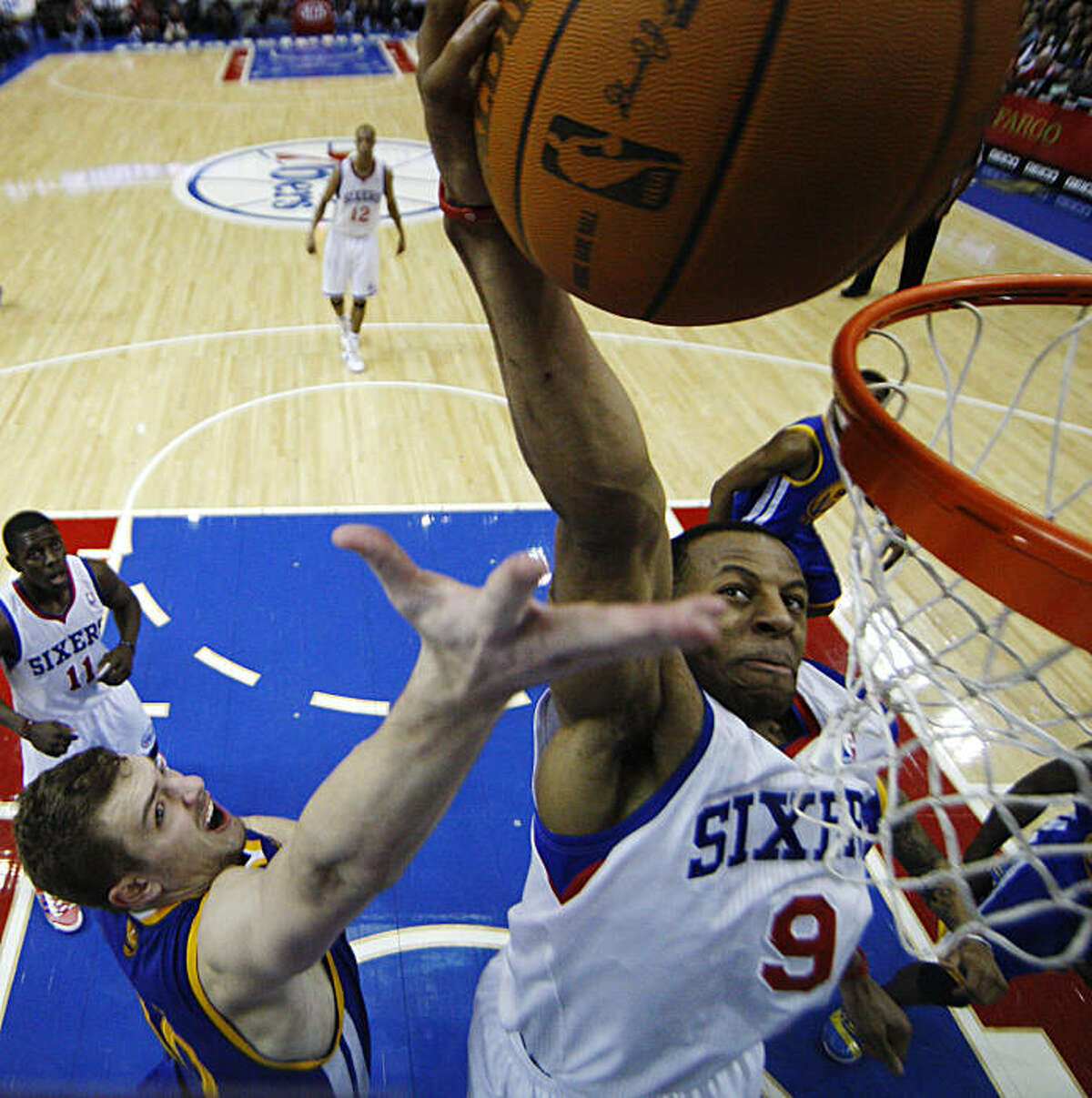 Philadelphia 76ers' Andre Iguodala, right, goes up for a dunk against Golden State Warriors' David Lee in the second half of an NBA basketball game Sunday, March 6, 2011, in Philadelphia. Philadelphia won 125-117 in overtime.