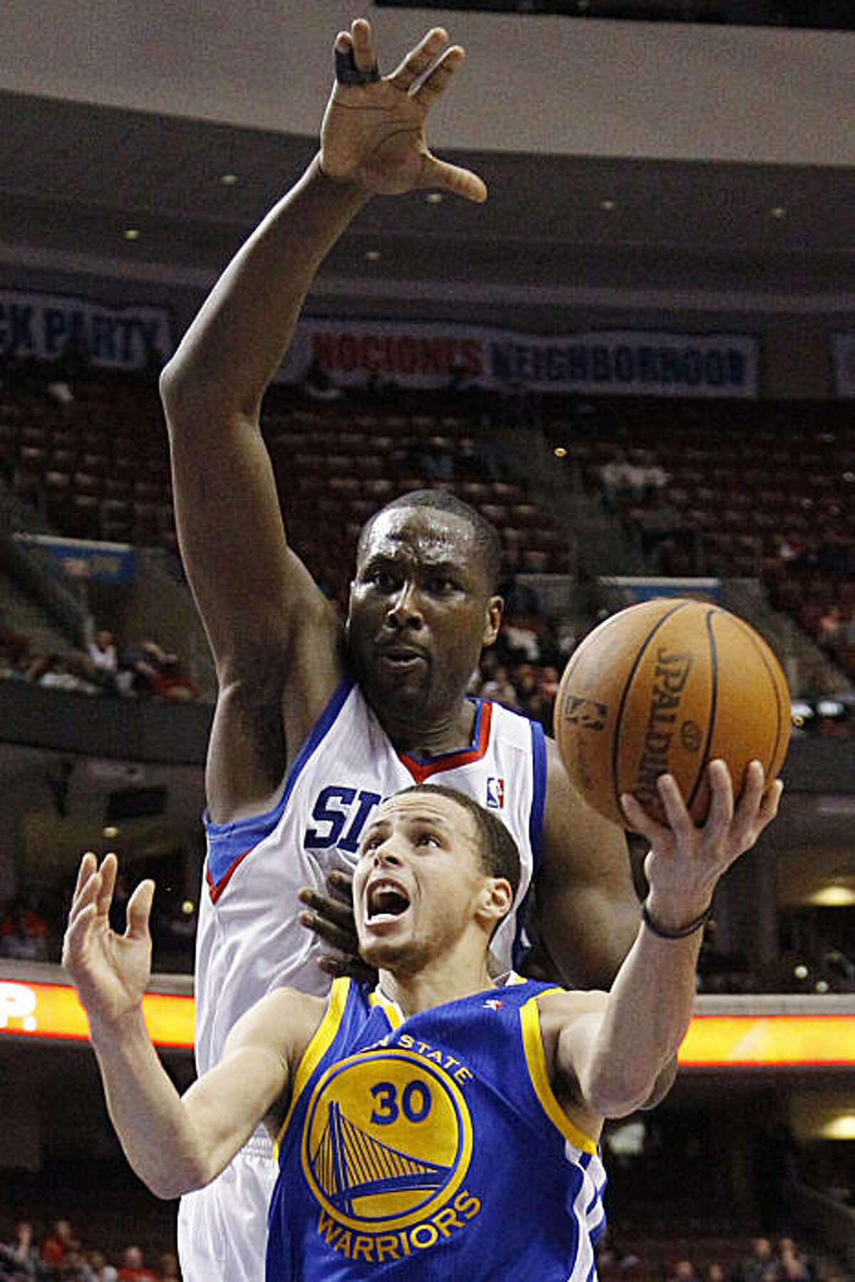 Golden State Warriors' Stephen Curry, bottom, goes up for a shot against Philadelphia 76ers' Elton Brand in the first half of an NBA basketball game on Sunday, March 6, 2011, in Philadelphia.