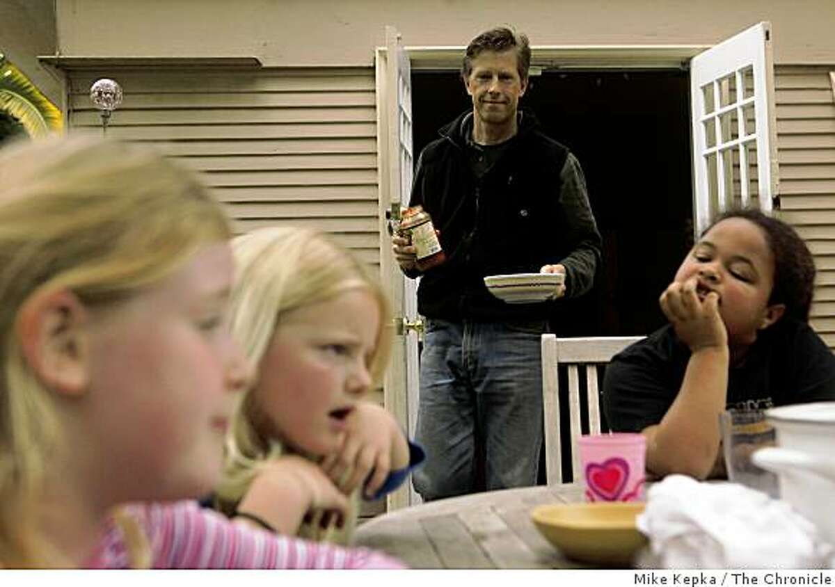 Jack Macy serves a spaghetti lunch in his back yard to eight-year-olds Caroline Hall (from left) Lydia Macy (his daughter) and Kiki Valenzuela, all second graders at Malcolm X Elementary on Tuesday April 28, 2009 in Berkeley, Calif. After receiving word that the school would be closed for at least a week due Swine Flu concerns, their parents decided that they would group resources and each take a day of the week to watch the kids. On Friday its likely they will have to hire a sitter.
