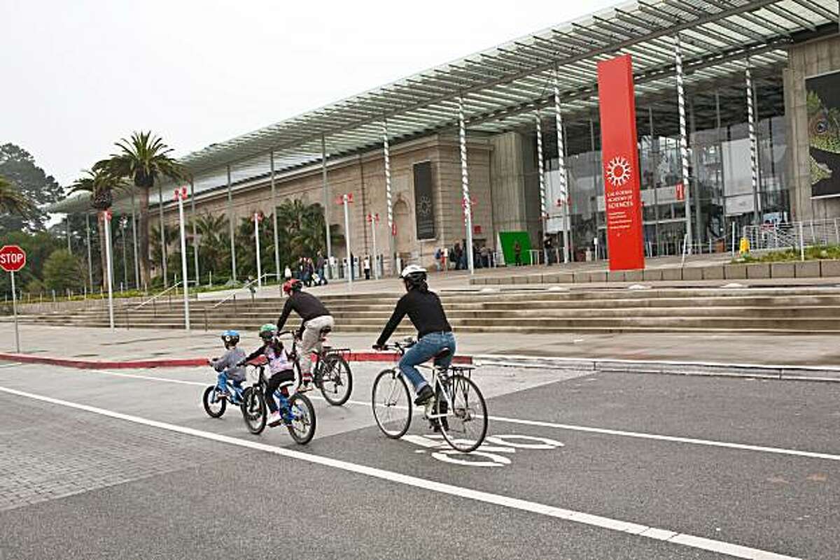 A family bikes by the California Academy of Sciences in Golden Gate Park.