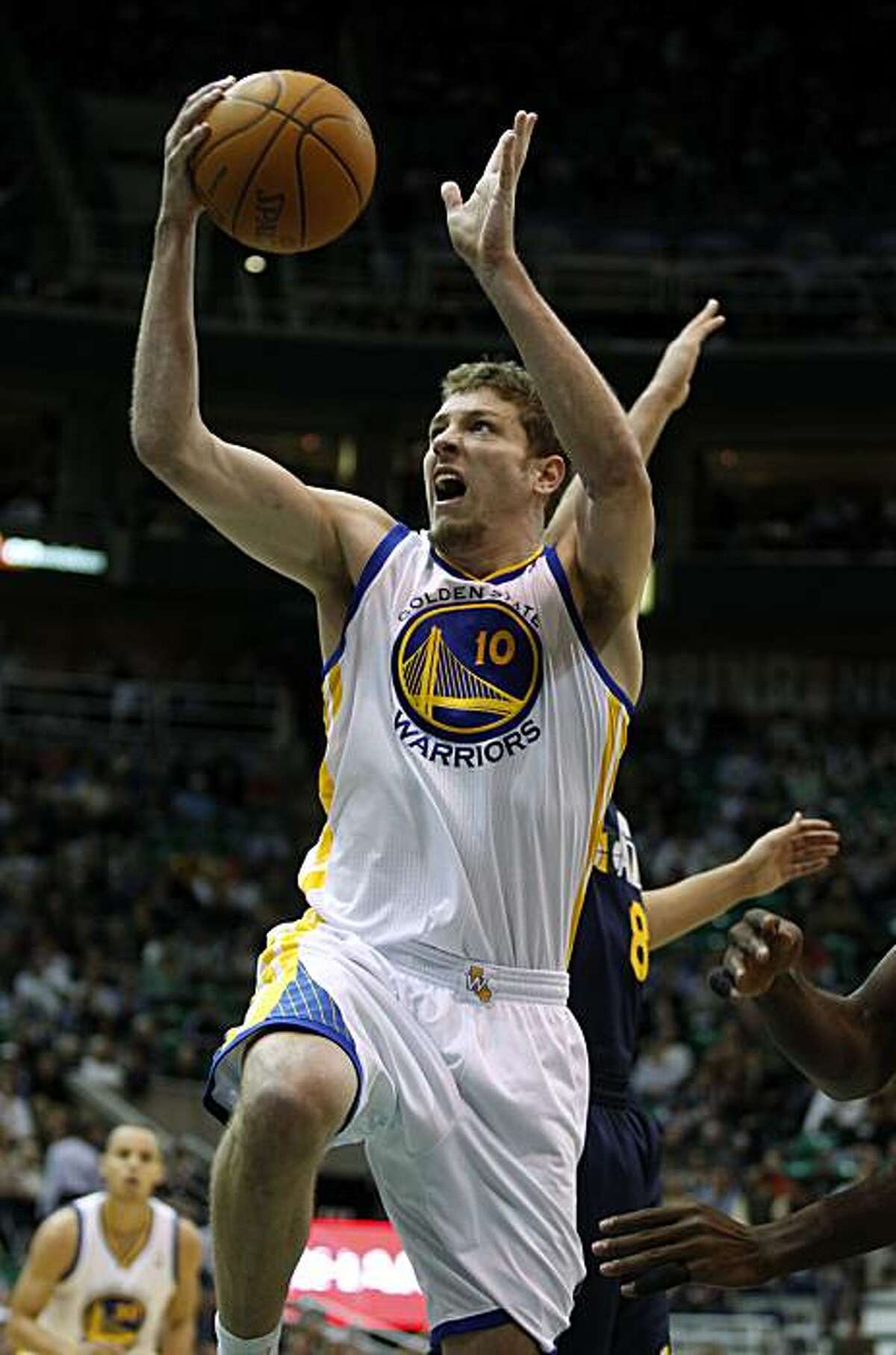 Golden State Warriors center David Lee (10) slips by Utah Jazz guard Deron Williams (8) for a basket during the first half of an NBA basketball game in Salt Lake City, Wednesday, Feb. 16, 2011.