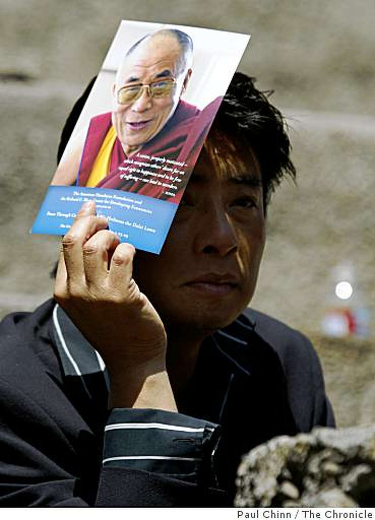 Pema Randul shields his face from the sun while waiting to hear the Dalai Lama speak about "Peace Through Compassion" at the Greek Theatre in Berkeley, Calif., on Saturday, April 25, 2009.