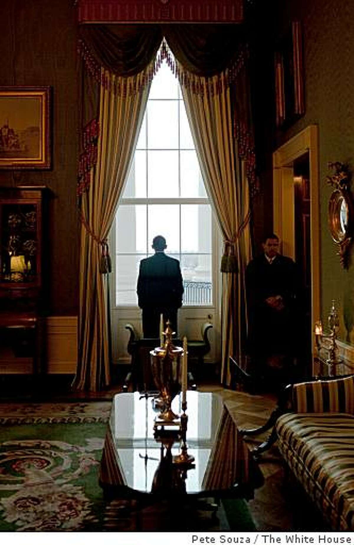President Barack Obama looks out the Green Room window prior to the "Open for Questions" virtual town hall meeting on the economy in the East Room on March 26, 2009.