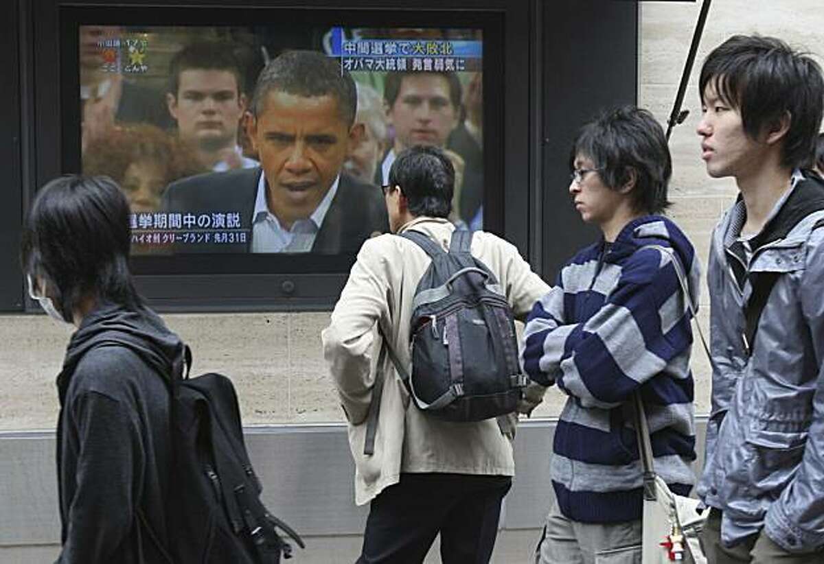 A man looks at a large TV screen showing U.S. President Barack Obama delivering a campaign speech, in central Tokyo Thursday, Nov 4, 2010. A chastened Obama signaled a willingness to compromise with Republicans on tax cuts and energy policy Wednesday, one day after his party lost control of the House and suffered deep Senate losses in midterm elections.