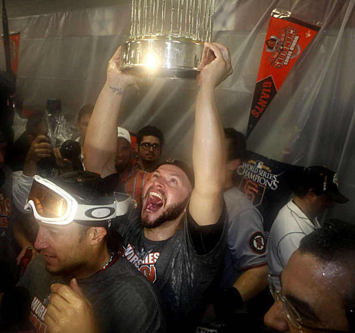 San Francisco Giants' Cody Ross (13) lifts the 2010 World Series Championship trophy over his head in the Visiting Clubhouse at Rangers Ballpark after the San Francisco Giants win Game 5 of the World Series over the Texas Rangers 3-1 on Monday November 1, 2010 in Arlington, Texas.