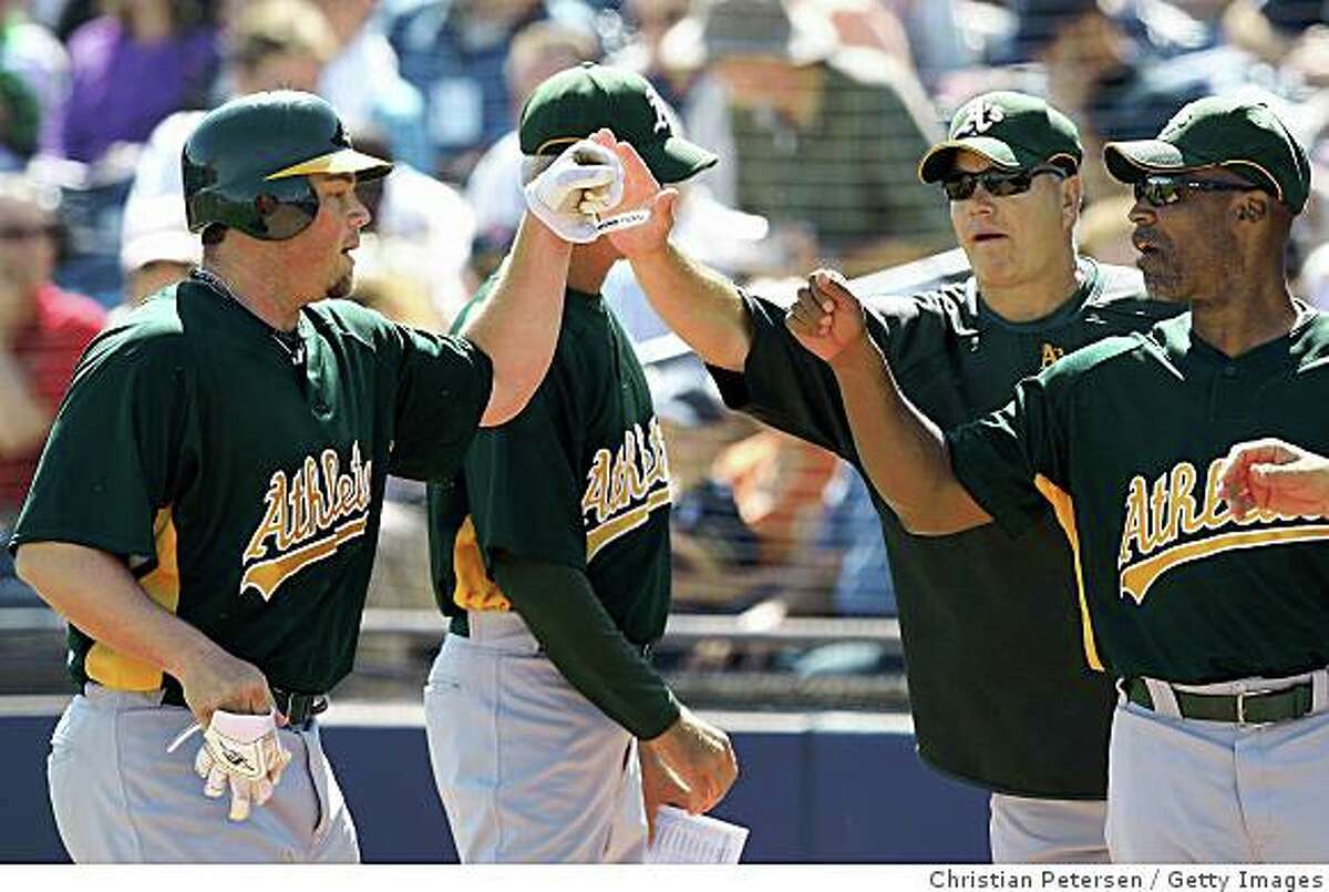 Landon Powell is congratulted by coaches Curt Young and Tye Waller after hitting a home run against the San Diego Padres during a spring training game at Peoria Stadium on March 7, 2009 in Peoria, Arizona.