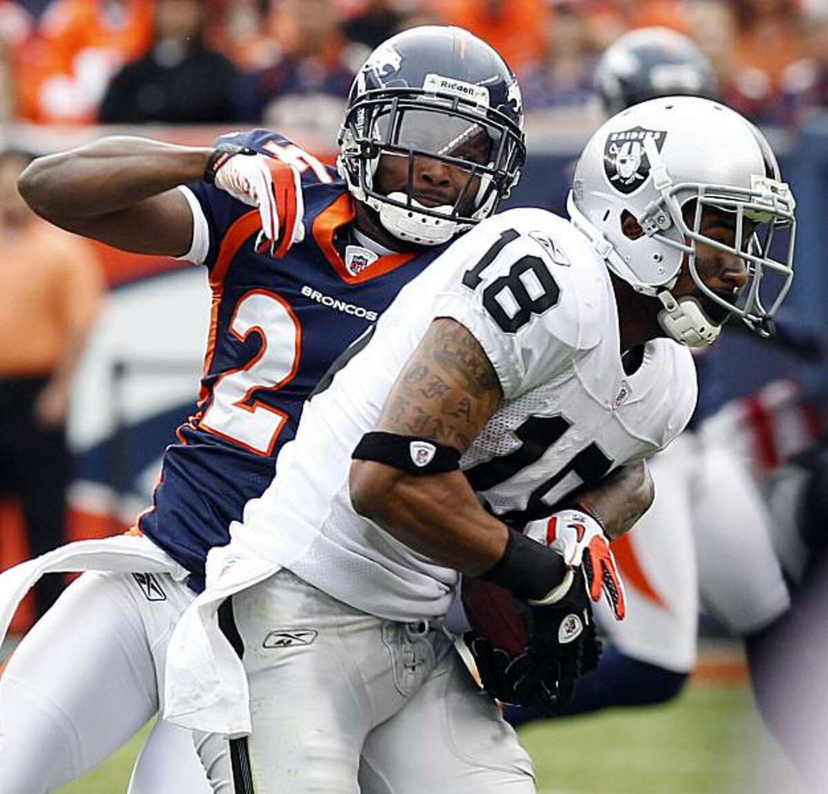 Denver Broncos cornerback Champ Bailey, left, breaks up a pass intended for Oakland Raiders wide receiver Louis Murphy (18) during the first half of an NFL football game, Sunday, Oct. 24, 2010, in Denver.