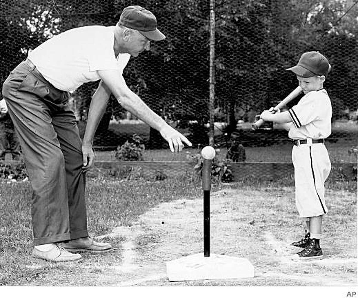 In a photo provided by Albion, Mich., historian Frank Passic, Jerry Sacharski, left, gives instructions to 5-year-old Craig LeClair in 1958. The Michigan man known for helping to popularize T-ball as an organized youth sport has died. The J. Kevin Tidd Funeral Home in Albion says Sacharski, 93, died Friday, Feb. 27, 2009, at his home in Albion. The game's exact origin is unclear but behind Sacharski, Albion in 1956 became one of the nation's first communities in which T-ball was played as an organized sport. (AP Photo/Frank Passic via Battle Creek Enquirer) ** NO SALES **