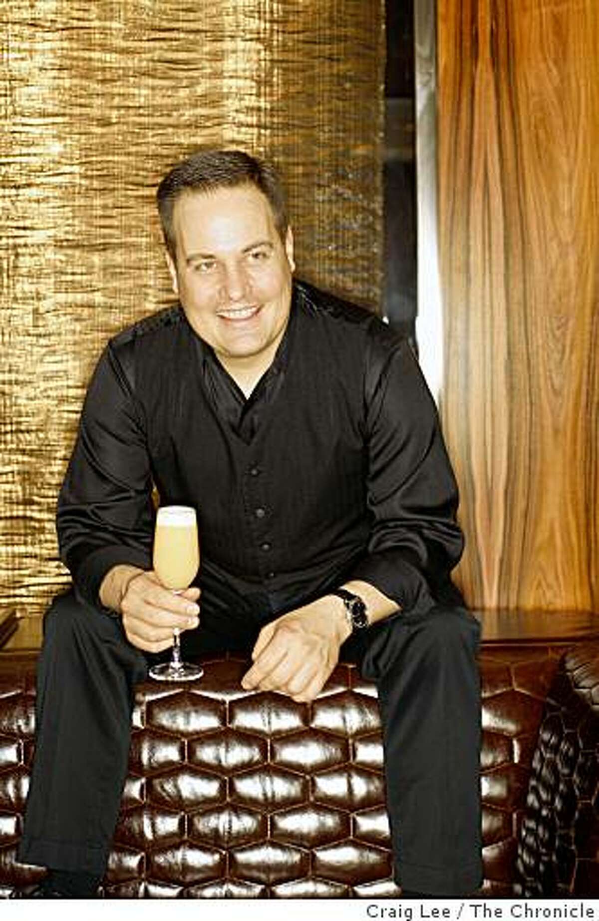 Marco Dionysos, bar manager at Clock Bar with his drink he created called English Breakfast in San Francisco, Calif., on February 18, 2009. Behind him is a curtain made of gold.