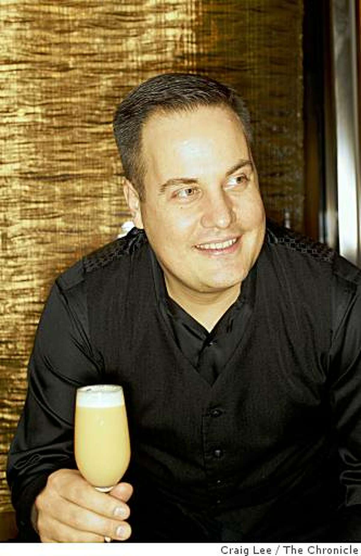 Marco Dionysos, bar manager at Clock Bar with his drink he created called English Breakfast in San Francisco, Calif., on February 18, 2009. Behind him is a curtain made of gold.
