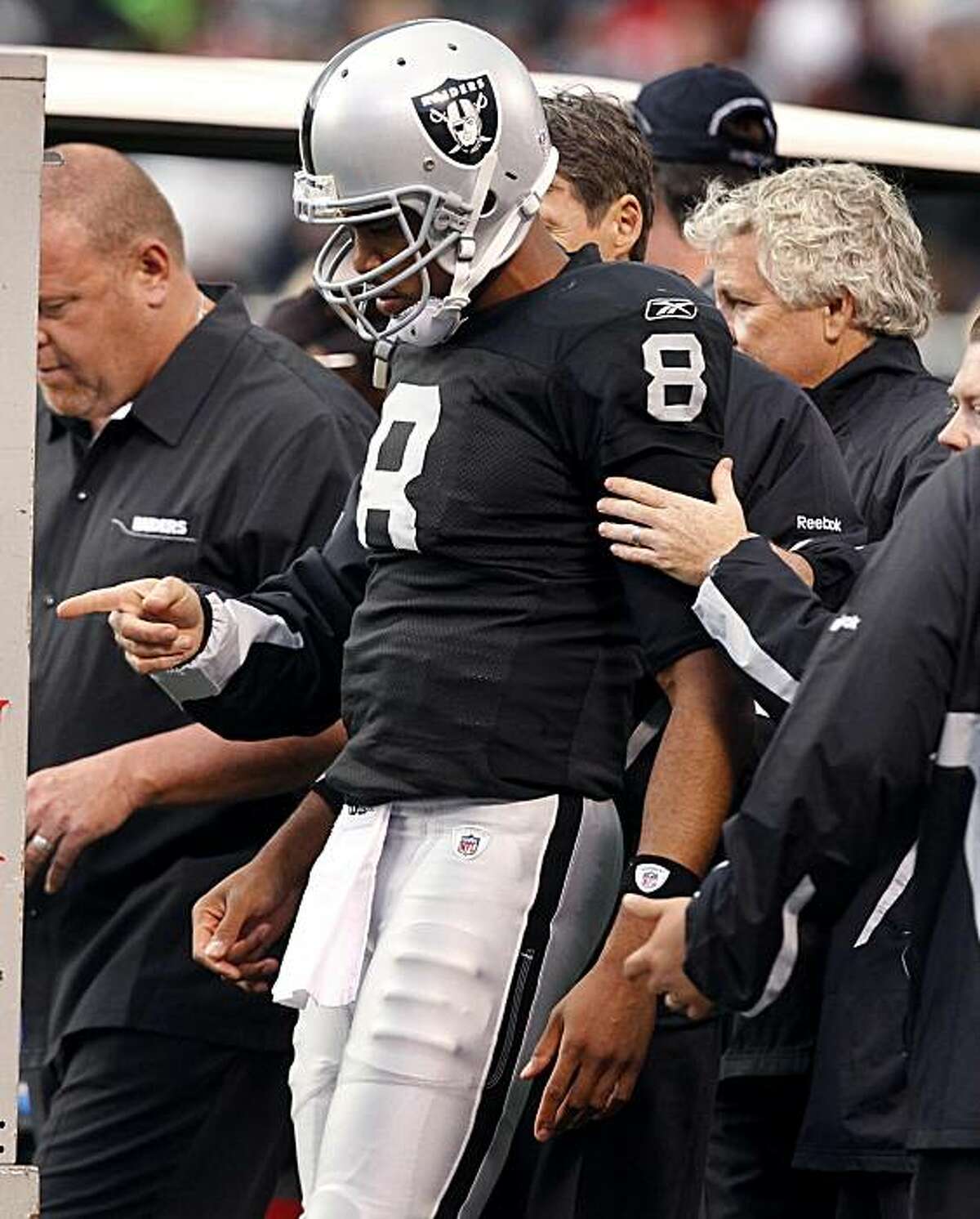 Raiders quarterback Jason Campbell is helped off the field after he left the game in the second quarter against the 49ers in Oakland on Saturday.