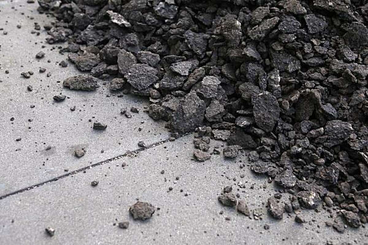 During a city repaving project, old asphalt spills onto the sidewalk on a stretch of Fell Street between Franklin and Polk Streets on Tuesday Oct. 5, 2010 in San Francisco, Calif.