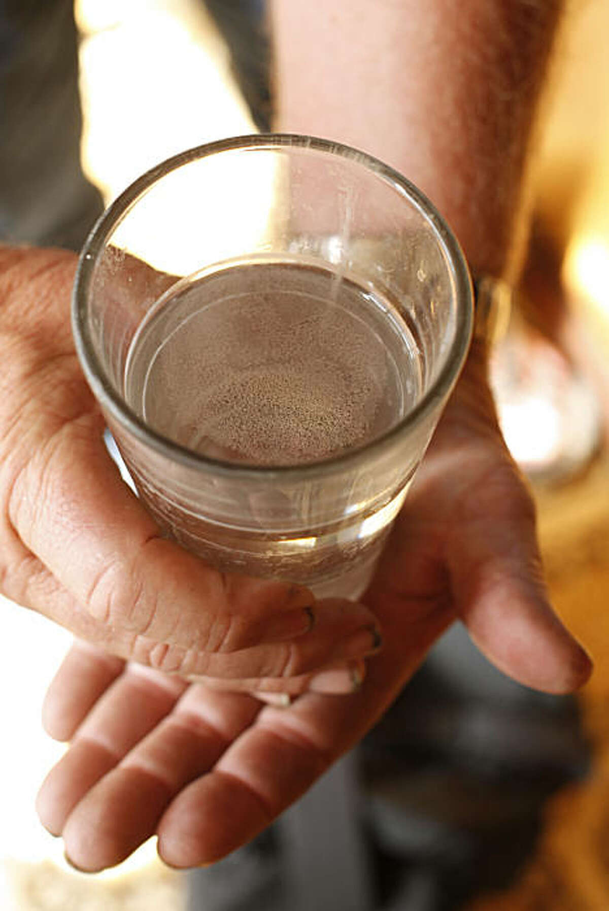 John Sanders, who lives near the Hilmar Cheese Company, holds a glass of water that has a white film floating on the surface in Hilmar, Calif., on August 20, 2010.