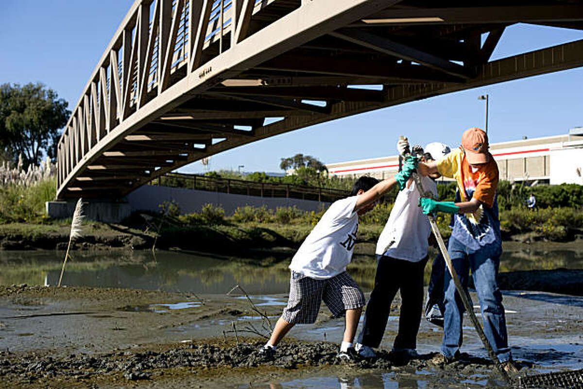 From right, Sean Vernon, Daniel Jun, Justin Chan, all 12, use a piece of wood that they found to dig a big piece of garbage out of the dirt at the water's edge at Save the Bay's Colma Creek location which attracted approximately 200 volunteers that picked up all kinds of trash in South San Francisco, Calif., on Saturday, September 25, 2010.