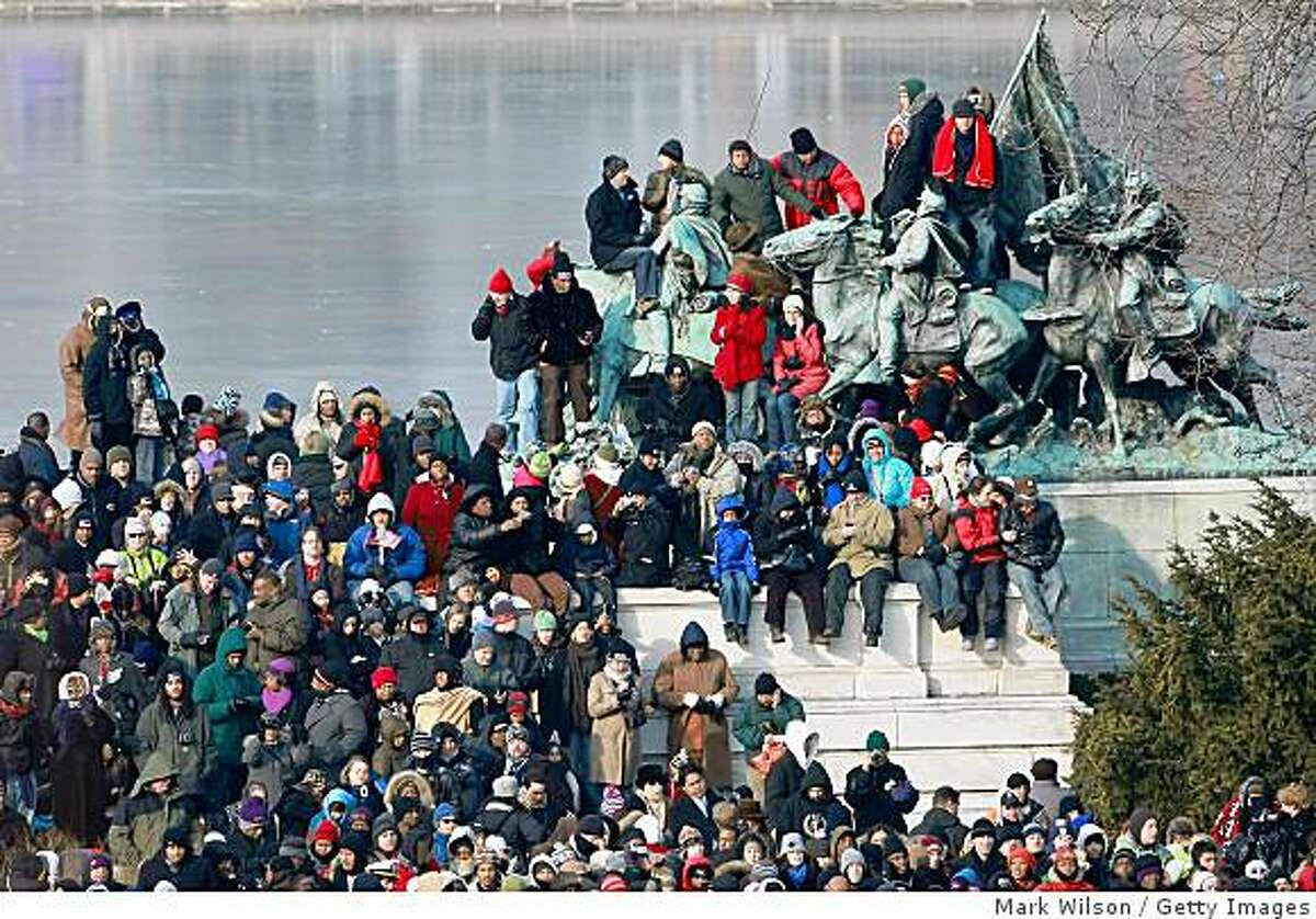 Crowds stand on a statue next to the on the National Mall ahead of the inauguration of Barack Obama.