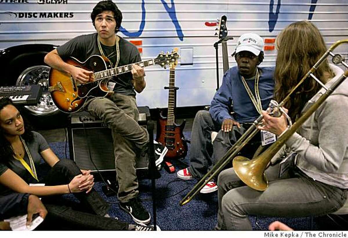 Surrounded by other young musicians from San Francisco and Zimbabwe, Adam Nash, a student from San Francisco's school of the Arts, works out a guitar part with other young musicians in front of the John Lennon Educational Tour Bus at the Macworld conference and Expo on Monday Jan. 5, 2009 in San Francisco, Calif.