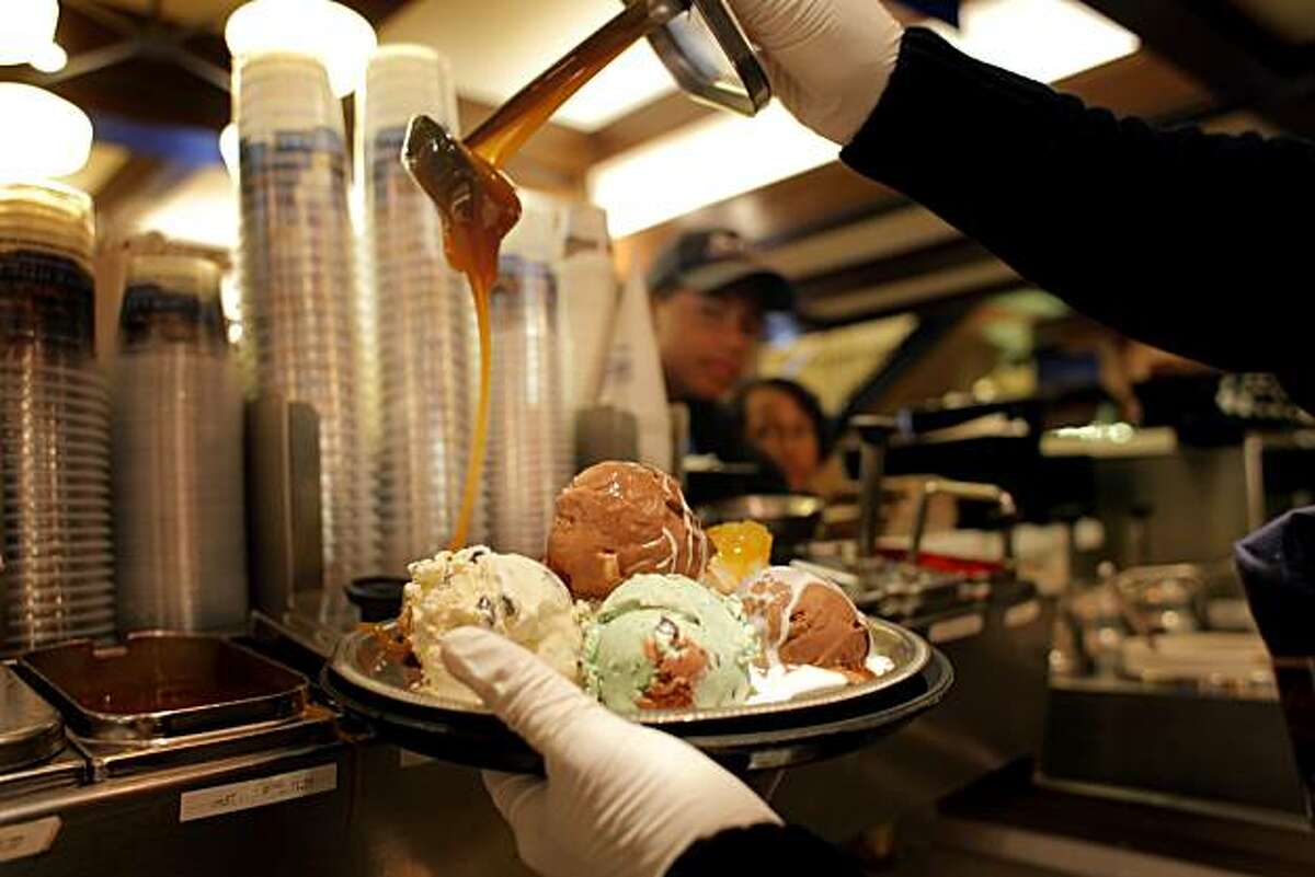 Pedro Mora pours the carmel on the earthquake ice cream sundae from Ghirardelli Square, as Jens and Bryce Bollesen from Gilroy watch it being made, Wednesday July 28, 2010, in San Francisco, Calif.