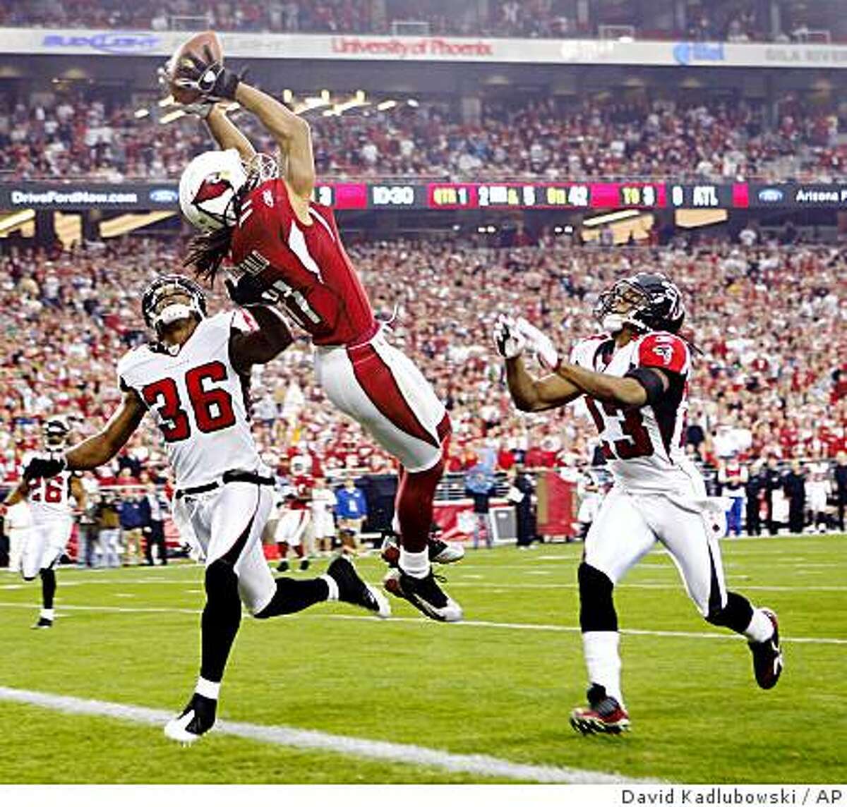 Arizona Cardinals wide receiver Larry Fitzgerald, center, catches the ball for a touchdown as Atlanta Falcons' Lawyer Milloy (36) and Chris Houston (23) defend during the first quarter of an NFC wild card playoff football game at the University of Phoenix Stadium in Glendale, Ariz, on Saturday, Jan. 3, 2009. (AP Photo/The Arizona Republic, David Kadlubowski ) ** MARICOPA COUNTY OUT, MESA TRIBUNE OUT, MAGS OUT, NO SALES **