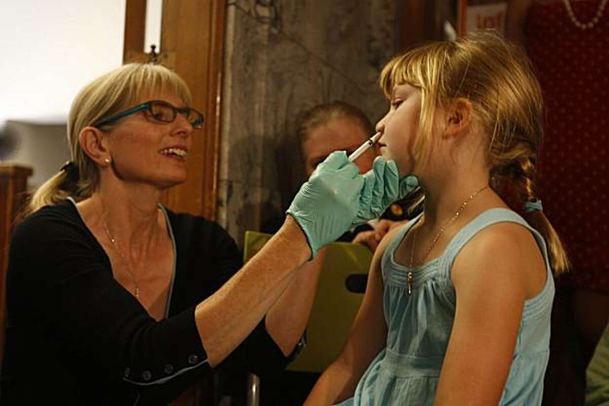 Dr. Susan Fernyak, (l to r) Director of Communicable Disease Control and Prevention gives Frances Pine-Rinella, whose mother Amy Pine works at the Public Health Deparment, the FluMist nasal vaccine at the Department of Public Health in San Francisco, Calif. on Thursday, September 3, 2009.