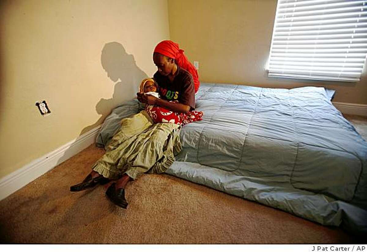 Marie Nadine Pierre and her baby, Nennon, sit on a mattress in a "people-less" house Wednesday, Nov. 26, 2008 in Miami. She is squatting in a bank foreclosured house. (AP Photo/J Pat Carter)