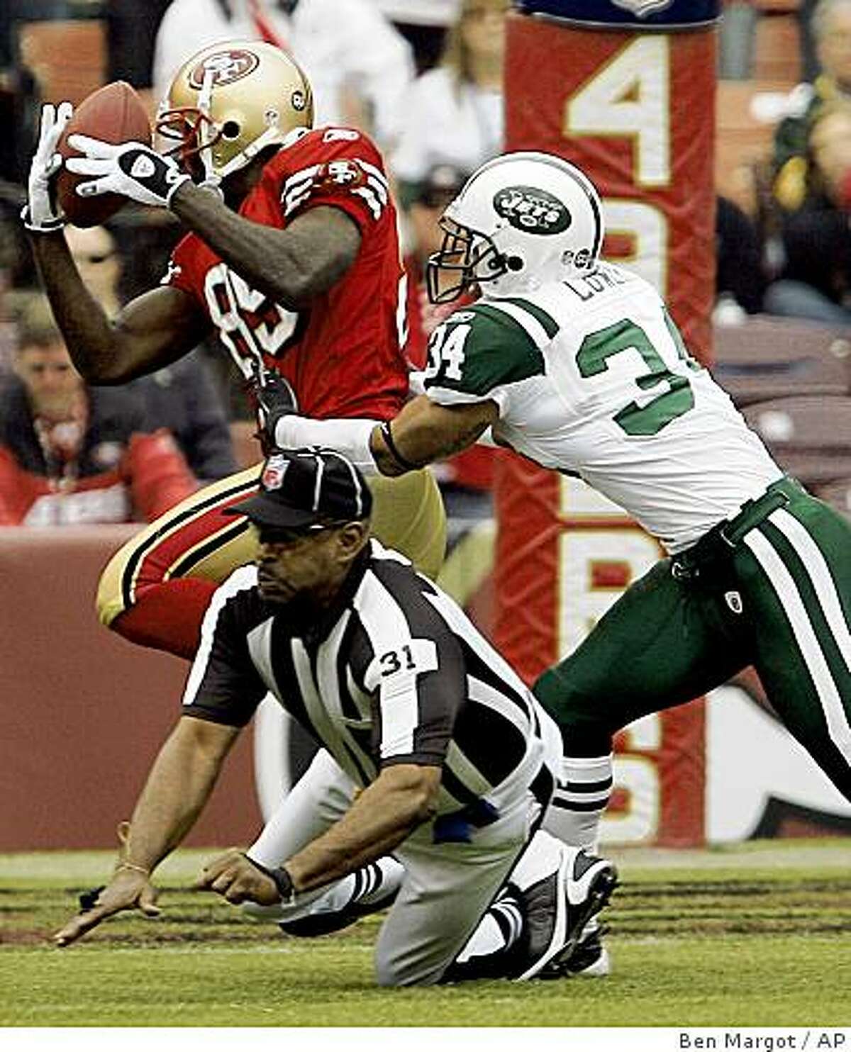 San Francisco 49ers' Vernon Davis, left, makes a reception past New York Jets' Dwight Lowery (34) as umpire Chad Brown (31) falls out of the way in the first half of an NFL football game Sunday, Dec. 7, 2008, in San Francisco. Davis fumbled the ball, which was picked up by 49ers' Joe Staley for a touchdown. (AP Photo/Ben Margot)
