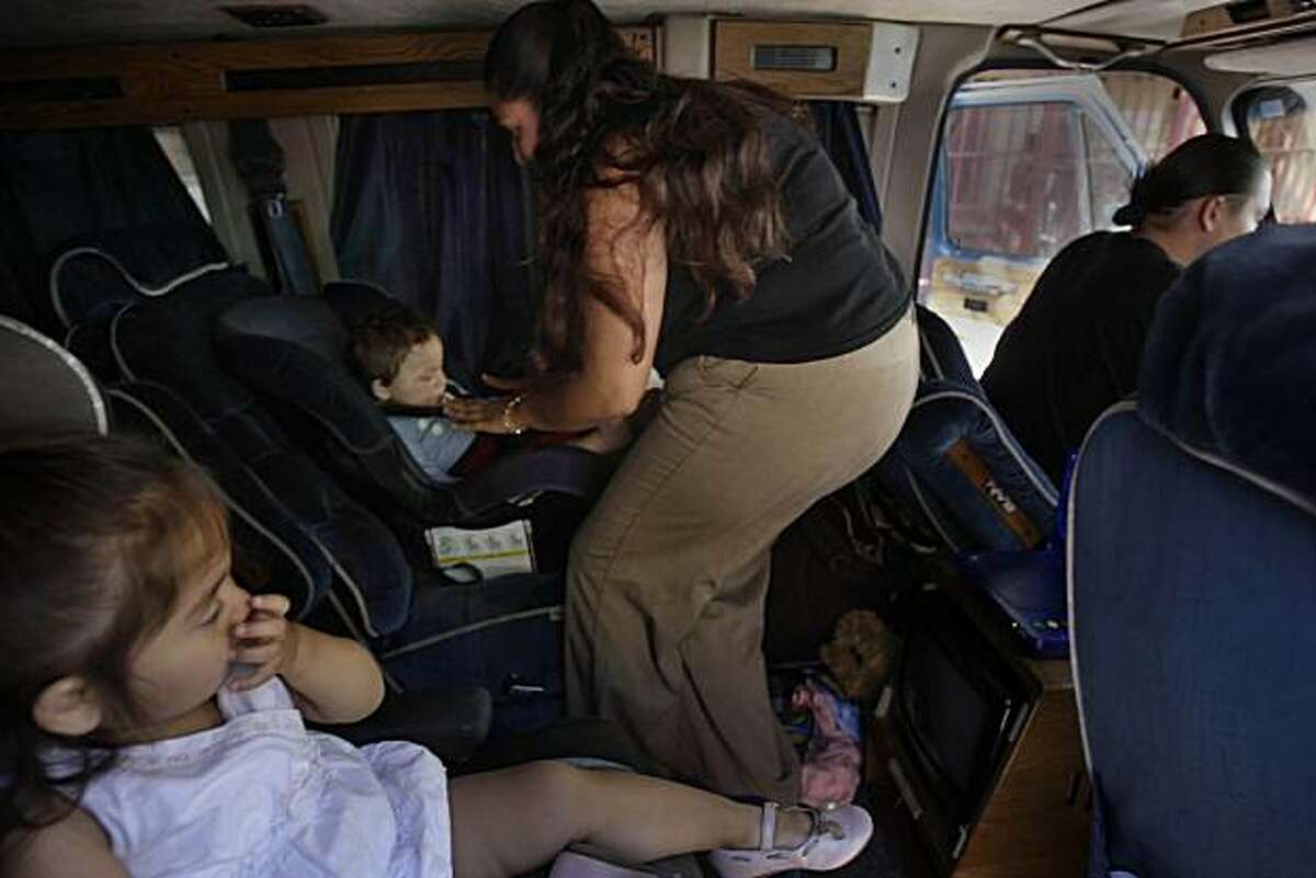 Lisa Romero (second from right) buckles her son, Anthony Robertson Jr. (second from left), 11 months, into his car seat before leaving for an outting with her daughter, Lisa Robertson (left), 1 year and 11 months, and her boyfriend Anthony Robertson (right) in San Francisco, Calif. on Thursday July 15, 2010.