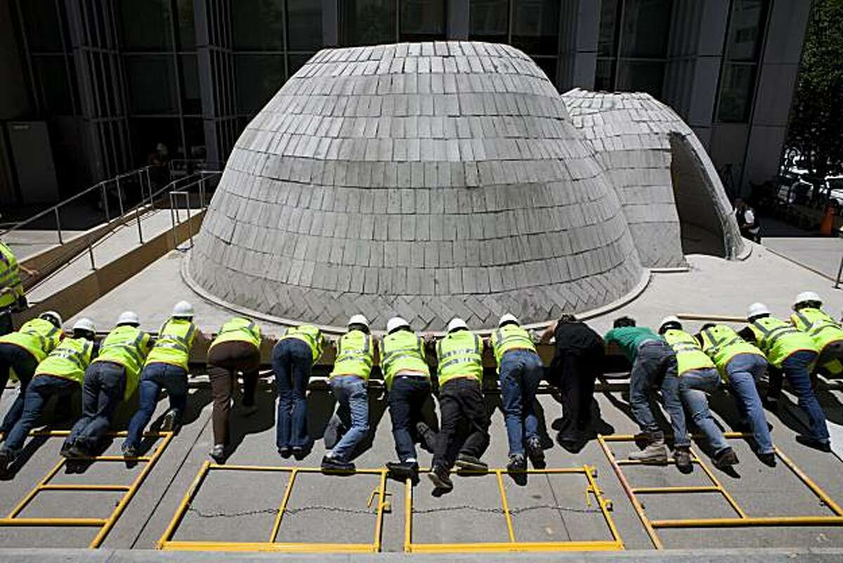 Volunteers push on the plywood foundation of the twin bowls at Yerba Buena Center (YBCA) for the Arts during the seismic test on Friday, July 2, 2010 in San Francisco.