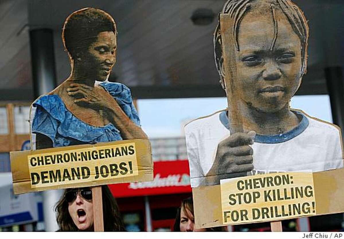 Carol Norris, left, holds up a sign at a protest at a Chevron gas station in San Francisco, Monday, Oct. 27, 2008. Norris and other activists rallied against Chevron's actions in Nigeria and to mark the opening of a human rights lawsuit against Chevron, Bowoto v. Chevron, in the U.S. Federal District Court in San Francisco. (AP Photo/Jeff Chiu)